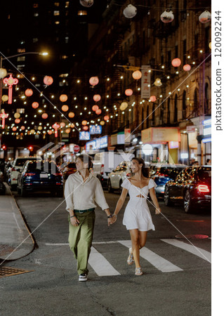Charming couple strolling under festive city lights, fully embracing their special moment 120092244