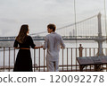 A Loving and Intimate Couple Embraces Tenderly with a Stunning Iconic Bridge in the Background 120092278