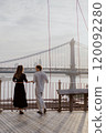 A Loving and Intimate Couple Embraces Tenderly with a Stunning Iconic Bridge in the Background 120092280