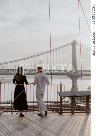 A Loving and Intimate Couple Embraces Tenderly with a Stunning Iconic Bridge in the Background 120092280