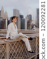 A Stylish Young Man is Relaxing on a Rooftop while Surrounded by a Beautiful Cityscape 120092281