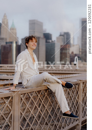 A Stylish Young Man is Relaxing on a Rooftop while Surrounded by a Beautiful Cityscape 120092281