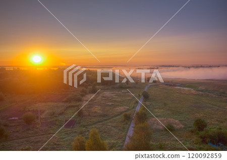 A Captivating Sunrise Over a Misty Landscape Featuring a Beautiful Tree Line and a Winding Pathway A Captivating Sunrise Over a Misty Landscape Featuring a Beautiful Tree Line and a Winding Pathway 120092859