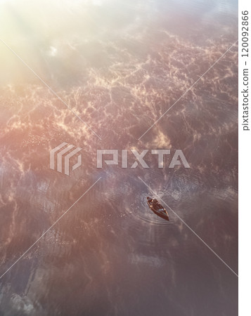 Enjoy a Serene Sunset Glowing Over Tranquil Waters While Observing a Small Boat Gliding Smoothly Enjoy a Serene Sunset Glowing Over Tranquil Waters While Observing a Small Boat Gliding Smoothly 120092866