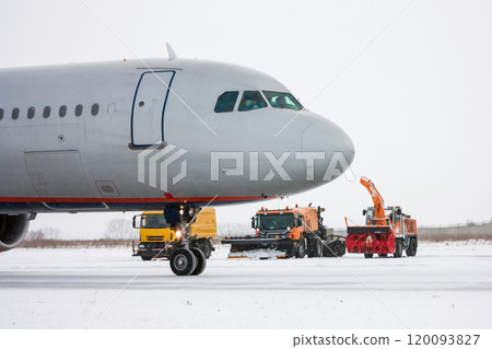 Airliner and snow removal equipment in a cold winter airport 120093827