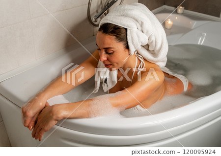 Pregnant woman with arms on tub in bubble bath 120095924