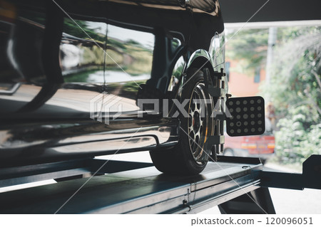 Closeup of car wheel alignment at auto repair center. Vehicle maintenance service in an automotive workshop with mechanical equipment for tire balance and adjustment. 120096051