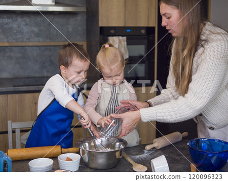 Mother and her children happily making cookie dough in a modern kitchen, bonding and learning together while creating a warm and joyful atmosphere, Dough Cooking Concept, a very young cook 120096323