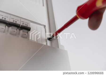 Close-up of a man unscrewing a screw with a screwdriver in an electric meter Close-up of a man unscrewing a screw with a screwdriver in an electric meter 120096688
