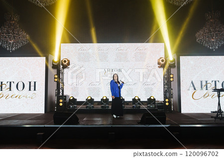 attractive woman in blue jacket on the stage in front of the big screen 120096702