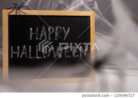 A board with the inscription Happy Halloween on a dark background. Spiders making a web 120096727