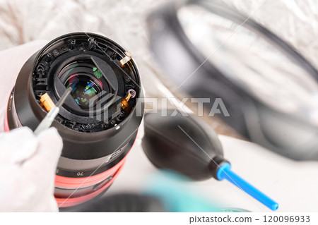 the hands of the master with gloves and a broken lens of a professional camera. 120096933