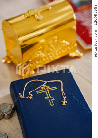 A baptismal cross on a chain lies on a blue Bible. A baptismal cross on a chain lies on a blue Bible. 120096988