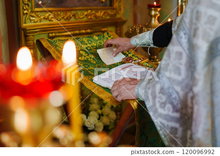A priest with a prayer book on a table conducts the service.  120096992