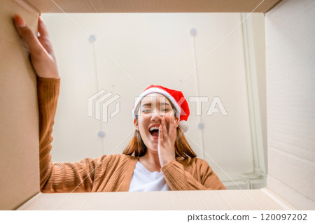 Low angle view of surprised young Asian woman wearing Christmas hat and unpacking Low angle view of surprised young Asian woman wearing Christmas hat and unpacking 120097202