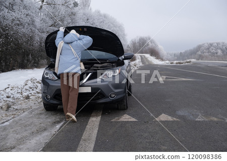 Woman watching at Car Engine on Snowy Roadside 120098386