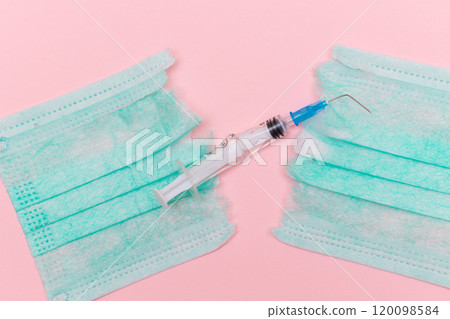 Broken Medical Syringe and Torn Medical Face Mask on the Pink Background 120098584