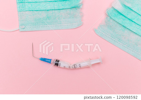 Broken Medical Syringe and Torn Medical Face Mask on the Pink Background 120098592