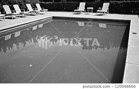 A clear view of a tranquil swimming pool, surrounded by empty lounge chairs on a sunny day 120098666