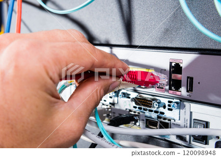 Hand of computer engineer connecting network cable in server cab Hand of computer engineer connecting network cable in server cab 120098948