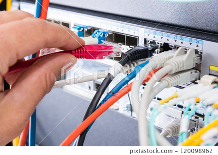 Hand of computer engineer connecting network cable in server cab Hand of computer engineer connecting network cable in server cab 120098962
