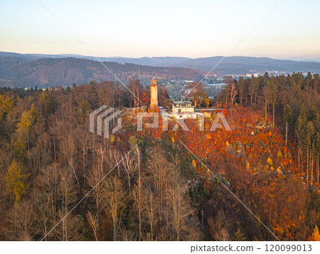 The lookout tower on Prosec Ridge stands tall against a backdrop of vibrant autumn foliage as the sun sets over the Jizera Mountains near Jablonec nad Nisou, creating a serene atmosphere. The lookout tower on Prosec Ridge stands tall against a backdrop of vibrant autumn foliage as the sun sets over the Jizera Mountains near Jablonec nad Nisou, creating a serene atmosphere. 120099013