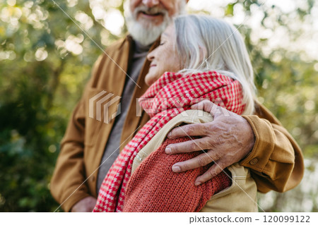 Close up of beautiful senior couple outdoors in an autumn garden. Elderly husband and wife are embracing each other. Close up of beautiful senior couple outdoors in an autumn garden. Elderly husband and wife are embracing each other. 120099122