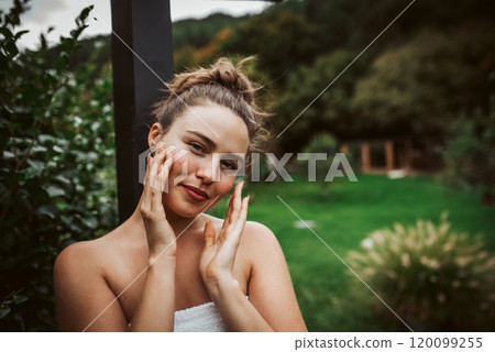 Beautiful woman touching her face, stainding outdoor in the garden. Woman taking care of her body and mind, wellness routine. Beautiful woman touching her face, stainding outdoor in the garden. Woman taking care of her body and mind, wellness routine. 120099255