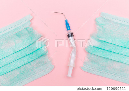 Broken Medical Syringe and Torn Medical Face Mask on the Pink Background Broken Medical Syringe and Torn Medical Face Mask on the Pink Background 120099511