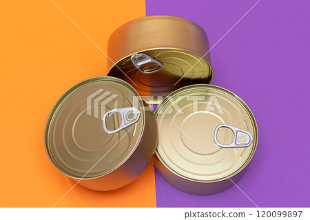 A Group of Stacked Tin Cans with Blank Edges on Split Orange and Violet Background 120099897