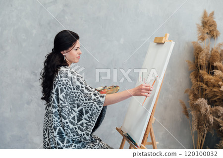 Female artist painting paintings with paints on canvas with easel 120100032