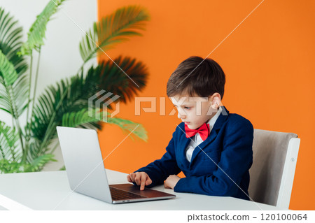 Little boy in business suit sitting at laptop Little boy in business suit sitting at laptop 120100064