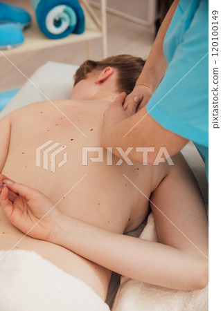 chiropractor doing medical back massage to woman in spa chiropractor doing medical back massage to woman in spa 120100149