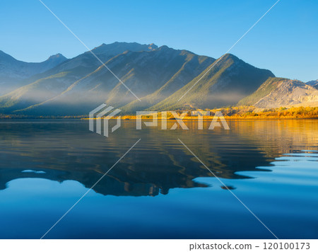 Mountain landscape at dawn. Sunbeams in a valley. Lake and high peaks in a mountain valley Mountain landscape at dawn. Sunbeams in a valley. Lake and high peaks in a mountain valley 120100173