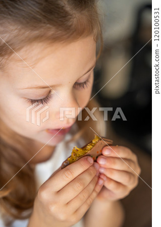 Little girl eating Dubai chocolate with pistachio paste and kataifi dough. Confectionery handmade sweets at home in the kitchen. Little girl eating Dubai chocolate with pistachio paste and kataifi dough. Confectionery handmade sweets at home in the kitchen. 120100531