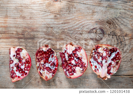 pomegranate divided into 4 pieces, on a wooden background, top view 120101438