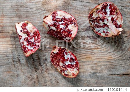 pomegranate divided into 4 pieces, on a wooden background, top view 120101444
