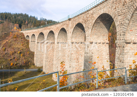 The historic railway viaduct in Smrzovka stands majestically under the clear sky, framed by autumn foliage in the Jizera Mountains, showcasing vibrant colors along the tranquil landscape. The historic railway viaduct in Smrzovka stands majestically under the clear sky, framed by autumn foliage in the Jizera Mountains, showcasing vibrant colors along the tranquil landscape. 120101456