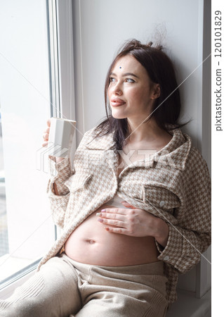 Pregnant woman enjoying a cup of coffee by the window. 120101829