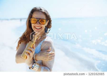smiling modern female on beach with sunscreen smiling modern female on beach with sunscreen 120102085
