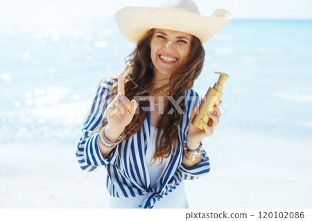 smiling stylish woman on ocean coast with spf 120102086