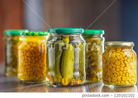 Canned vegetable. Pickled corn, cucumbers and jalapeno peppers on wooden table. 120102102