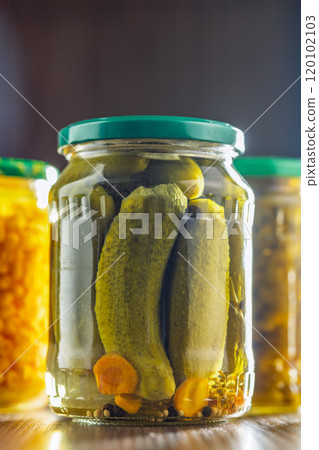 Pickles. Marinated cucumbers in jar on wooden table. 120102103