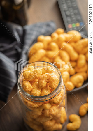 Puffed crispy Peanut flips in jar on wooden table. 120102116