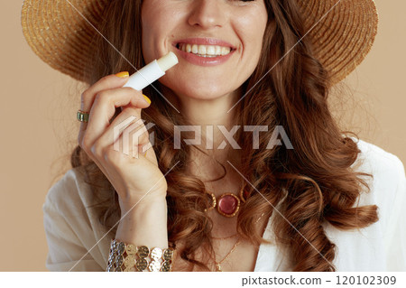 smiling trendy female in blouse and shorts against beige 120102309