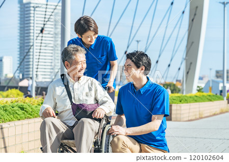 A caregiver talking to a senior man in a wheelchair 120102604