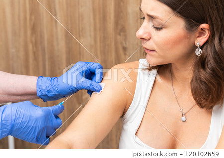 Medical assistant in gloves preparing patients arm for vaccination 120102659
