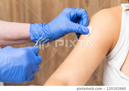 Medical assistant in gloves preparing patients arm for vaccination 120102660