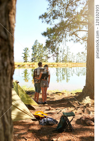 Into the woods. Shot of a young couple camping by a lake. 120102935