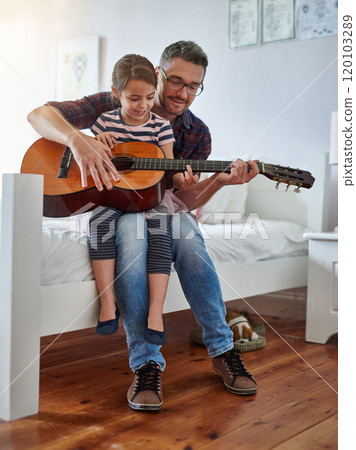 They have a lot in common. Shot of a little girl playing the guitar with her father. They have a lot in common. Shot of a little girl playing the guitar with her father. 120103289